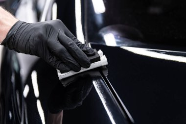 Araba yıkama ya da stüdyo çalışanı, koyu parlatıcı ve gelişmiş koruma sağlayan siyah araba boyasına seramik ya da grafen kaplama uygular.