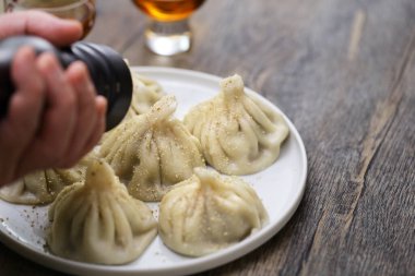 Biber değirmeninden biber öğütücü ev yapımı Khinkali köfteleri, Gürcistan geleneksel yemekleri.
