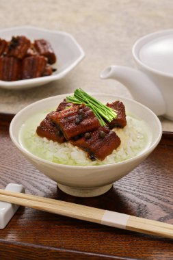 Sıcak yeşil çay pilavın üzerine dökülür. Üzerine tatlı soya sosuyla haşlanmış yılan balığı, ev yapımı Japon mutfağı.