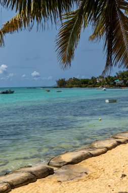 Güneşli bir günde mercan resifinin yanındaki kayalık plajda mavi gökyüzü ve açık bulutlu Kaptan Mauritius.