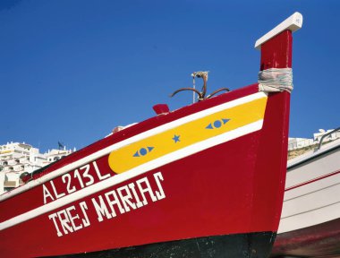 ALBUFEIRA, PORTUGAL-JANUARY 05: 2019: açık mavi gökyüzü ile sahilde renkli balıkçı teknesi. Arka plandaki yazlık evlerde.