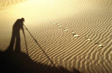 Mesquite Düz Kum tepelerinde çöl sabahı. Kaliforniya 'daki Ölüm Vadisi Ulusal Parkı' ndaki kum tepeleri boyunca ayak sesleri. Gün batımında bir fotoğrafçının gölgesi. .