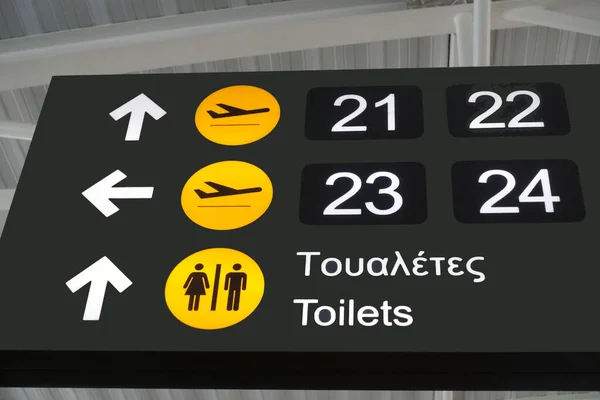 Sign to departure gates and toilets at the airport with Greek and English language.