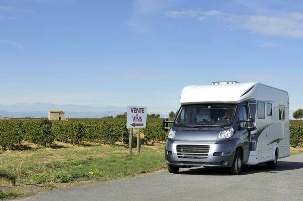 Camper at a road in France near a vineyard. At the sign is written in French that they sell wine