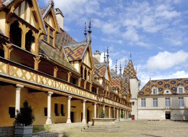 BEAUNE, FRANCE- MAY,13,2024: Hospices de Beaune or Hotel-Dieu de Beaune is a former charitable almshouse in Beaune, France. Courtyard, internal facade with polychrome roof.Without people clipart