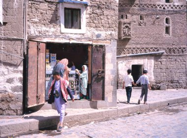 SADAA, YEMEN- 25 NİSAN 2011: küçük bir marketin yakınında kadın ve adamla sokak. Yürüyen iki küçük oğlan.