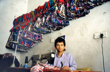 SANAA, YEMEN- 23 Nisan 2011: Dikiş makinesiyle çalışan genç bir Yemen 'li çocuk; korkunç çalışma koşullarında yasadışı çocuk işçiliği. 