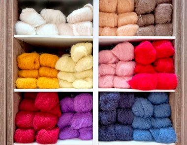 Farklı renklerde yün dolu bir zanaat dükkanında raflar