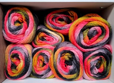 Çok renkli yün toplarıyla dolu bir zanaat dükkanında bir raf. 