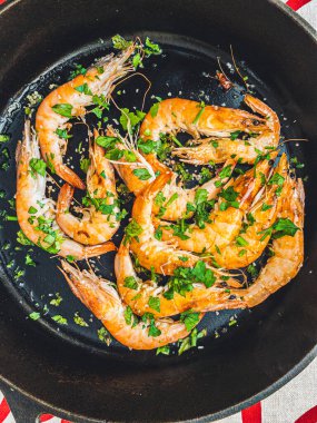Grilled Prawns with parsley in a frying pan.