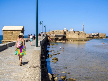 Cadiz, İspanya - 1 Ağustos 2023. La Caleta Sahili 'nde güneşlenen insanlar, arka planda La Caleta Adası' ndaki bir kale olan San Sebastian Kalesi. Görüntü: Paseo Fernando Quinones Güvertesi. Cadiz. Endülüs, İspanya.