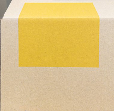A close-up of a cardboard box with a large yellow adhesive label