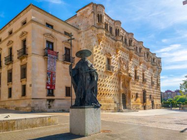 Guadalajara, Spain - April 14, 2024. Main facade of the Palace of El Infantado, with the bronze statue of Cardinal Mendoza in the foreground. Castilla la Mancha, Guadalajara, Spain. clipart
