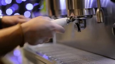 Barista, arka planda buharlı klasik bir İtalyan kahve makinesiyle espresso yapıyor..