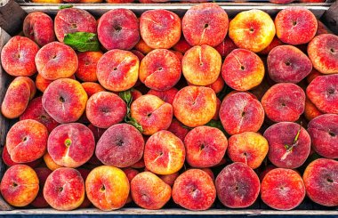 Satürn şeftalilerinin, pazardaki ahşap bir sandıkta dizilmiş taze görüntüsü..