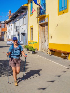 Sırt çantalı, sırıklı bir yürüyüşçü Camino de Santiago rotasındaki bir seyyah Albergue 'den ayrılıyor ve uzaklaşıyor. İspanya.