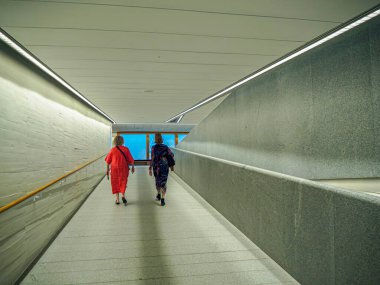 Madrid, Spain - September 24, 2024. Two women on a ramped corridor providing accessibility between floors at the Royal Collections Gallery Museum, located within the Royal Palace complex in Madrid. clipart