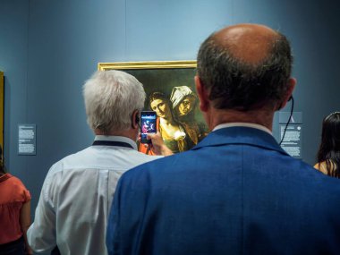 Madrid, İspanya - 24 Eylül 2024. Bir turist, Madrid Kraliyet Sarayı kompleksi Kraliyet Koleksiyonları Galerisi 'nde Caravaggio tarafından Vaftizci Yahya' nın Başkanıyla Salome 'nin fotoğrafını çekiyor..