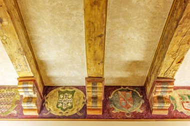 Guadalajara, Spain - November 8, 2024. Painted beams, wooden frieze, and capitals adorned with coats of arms and candelieri motifs in the central hall of Palacio de Davalos, now serving as the public library. clipart