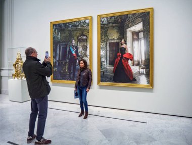 Madrid, Spain - December 3, 2024. Visitors at The Tyranny of Chronos exhibition in Banco de Espana, admiring royal portraits of Spanish Kings by Annie Leibovitz depicting the Spanish monarchy. clipart