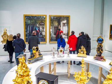 Madrid, Spain - December 3, 2024. Visitors at The Tyranny of Chronos exhibition in Banco de Espana, admiring royal portraits of Spanish Kings by Annie Leibovitz depicting the Spanish monarchy. clipart