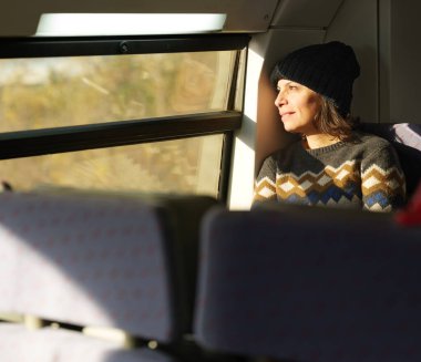 Tren vagonunun camından dışarı bakıp nefes kesici manzaranın tadını çıkaran nostaljik bir yolcu..