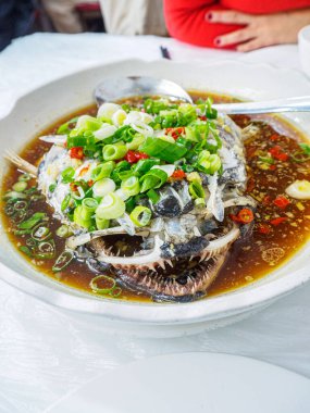 Geleneksel Çin balık kafası çorbası, yeşil soğan, acı biber ve sebze çorbası, seramik kasede sıcak olarak servis edilir..