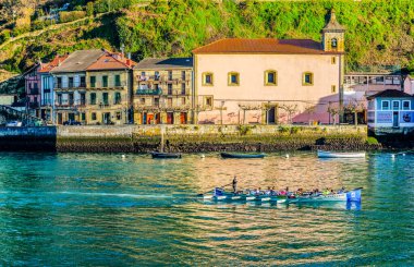 Pasai Donibane (San Juan), İspanya - 15 Ocak 2025 Trainera 'da bir kürek takımı Pasaia Limanı' nın sularında süzülüyor. Arka planda San Juan, Pasajes 'in renkli balıkçı köyü evleri var..