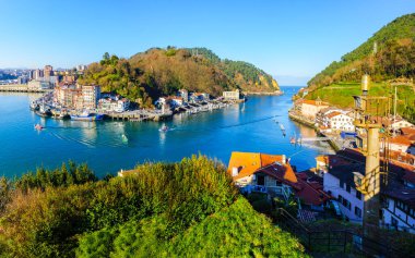 Pasajes, Spain - December 29 2024. Scenic view of the fishing port and bay of Pasajes, with colorful fishing boats traversing the waters. Basque Country, Spain. clipart