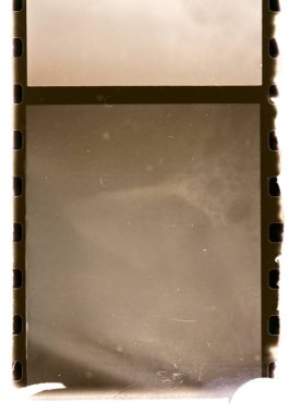 Kenarlarında delinmeler, sepya tonlu doku ve eski analog fotoğrafçılık materyallerine benzeyen küçük çizikler bulunan boş bir klasik film negatif çerçevesi..