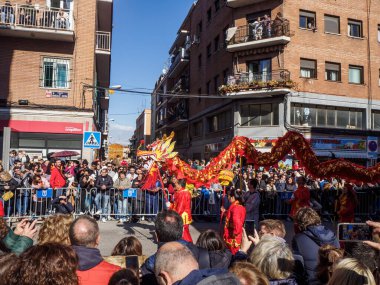 Madrid, İspanya - 2 Şubat 2025. Çin Yeni Yılı 'nda Madrid, Usera' da bir ejderha dansı geçidi gerçekleşir. Kırmızılı oyuncular ejderhaya rehberlik eder. Seyirciler anı izleyip yakalar..