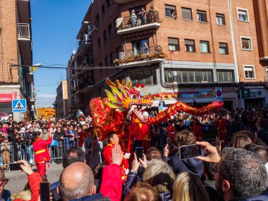 Madrid, İspanya - 2 Şubat 2025. Çin Yeni Yılı 'nda Madrid, Usera' da bir ejderha dansı geçidi gerçekleşir. Kırmızılı oyuncular ejderhaya rehberlik eder. Seyirciler anı izleyip yakalar..