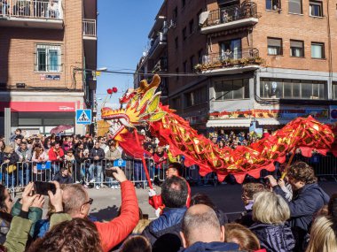 Madrid, İspanya - 2 Şubat 2025. Çin Yeni Yılı 'nda Madrid, Usera' da bir ejderha dansı geçidi gerçekleşir. Kırmızılı oyuncular ejderhaya rehberlik eder. Seyirciler anı izleyip yakalar..