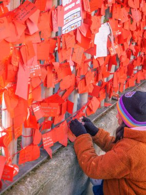 Madrid, İspanya - 2 Şubat 2025. Genç bir kız, Çin 'in Usera, Madrid Çin Mahallesi' nde yeni yılda şans ve mutluluk dileme geleneği olan notlarla dolu bir dilek duvarına kırmızı bir dilek kartı bağlıyor..