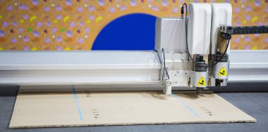 Dijital ölçekli kesim makinesi kıvrımlı karton kesiyor. Endüstriyel üretim.