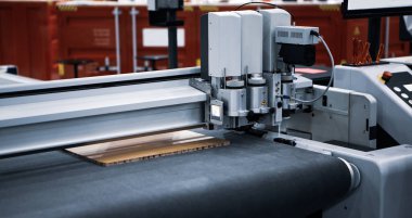 Dijital lazer ölçekli kesim makinesi kıvrımlı karton kesiyor. Endüstriyel üretim.