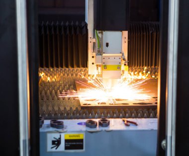 CNC fiber lazer kesme makinesi uçan kıvılcımlarla metal yaprak kesiyor. Endüstriyel metal üretimi.