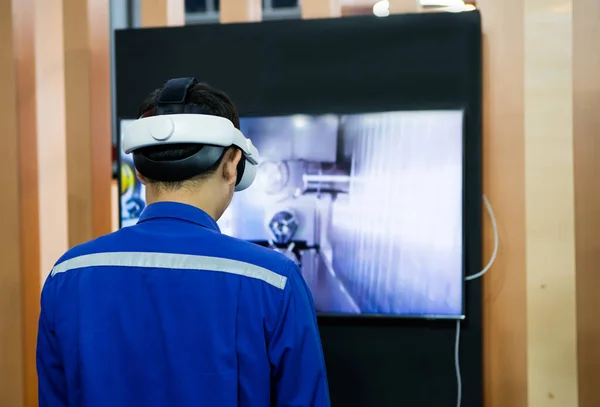 Industrial technician use VR goggle to operate machine.