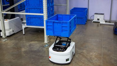 Modern endüstriyel depodaki çok katmanlı raflardan otonom robot malzemeleri topluyor..