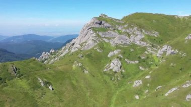 İnsansız hava aracıyla yüksek dağ tortulu kayaların, tepelerin ve yeşil yamaçların havadan görünüşü. Ciucas dağları, Karpatlar, Romanya