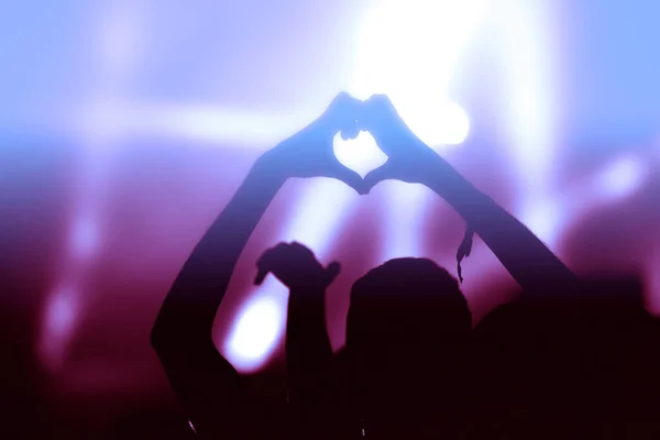 明るいステージライトの前でコンサートで愛のサインをする手 エンターテインメントコンセプト — ストック写真