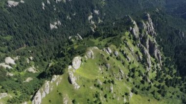 İnsansız hava aracıyla yüksek dağ tortulu kayaların, tepelerin ve yeşil yamaçların havadan görünüşü. Ciucas dağları, Karpatlar, Romanya
