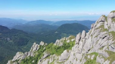 İnsansız hava aracıyla yüksek dağ tortulu kayaların, tepelerin ve yeşil yamaçların havadan görünüşü. Ciucas dağları, Karpatlar, Romanya