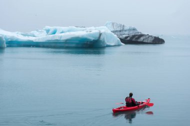 JOKULSARLON, ICELAND - 22 Mayıs 2019: Jokulsarlon buzulları arasındaki buzul gölünün dondurucu sularında bir kanoda kürek çeken adam