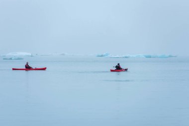 JOKULSARLON, ICELAND - 22 Mayıs 2019: Jokulsarlon buzulları arasındaki buzul gölünün dondurucu sularında bir kanoda kürek çeken adam