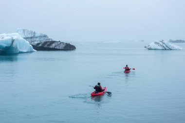 JOKULSARLON, ICELAND - 22 Mayıs 2019: Jokulsarlon buzulları arasındaki buzul gölünün dondurucu sularında bir kanoda kürek çeken adam