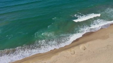Uzaktan kumlu bir sahil ve insansız hava aracıyla deniz dalgaları.