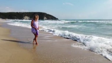 Muhteşem sarışın kadın sahilde özgürlüğün tadını çıkarıyor. Deniz dalgaları kumlu kıyıları yıkıyor