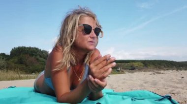 Güzel sarışın kadın sahilde bikinili sigara içiyor.