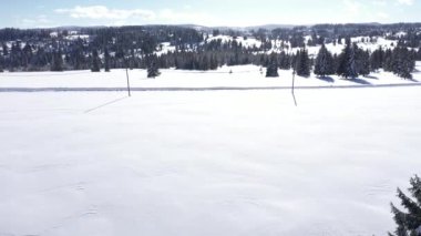  Dağlardaki her yer yemyeşil ormanlarla kaplı karların üzerinde uçuyordu. Kışın köknar ağaçlarının hava aracı görüntüsü